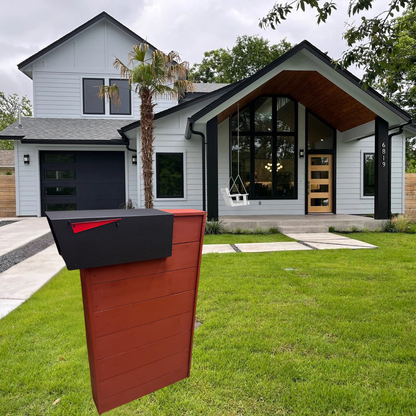 Red and black mailbox post in front of a modern house with a palm tree.